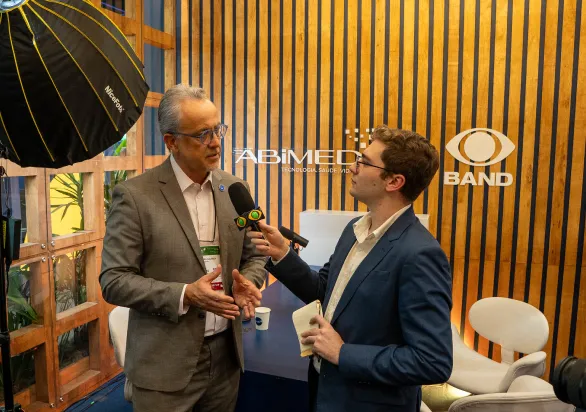 Homem de terno sendo entrevistado por um repórter da band.