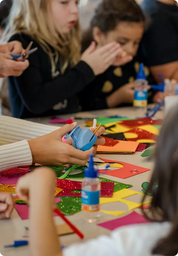 Crianças na mesa brincando de fazer recortes.